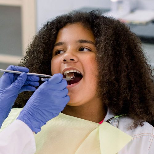 girl with curly hair getting teeth examined
