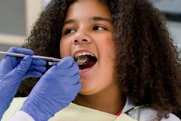 girl with curly hair getting teeth examined